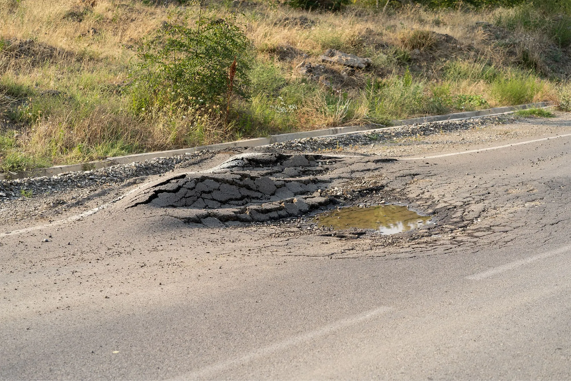 Deformed asphalt with potholes melts from heat due